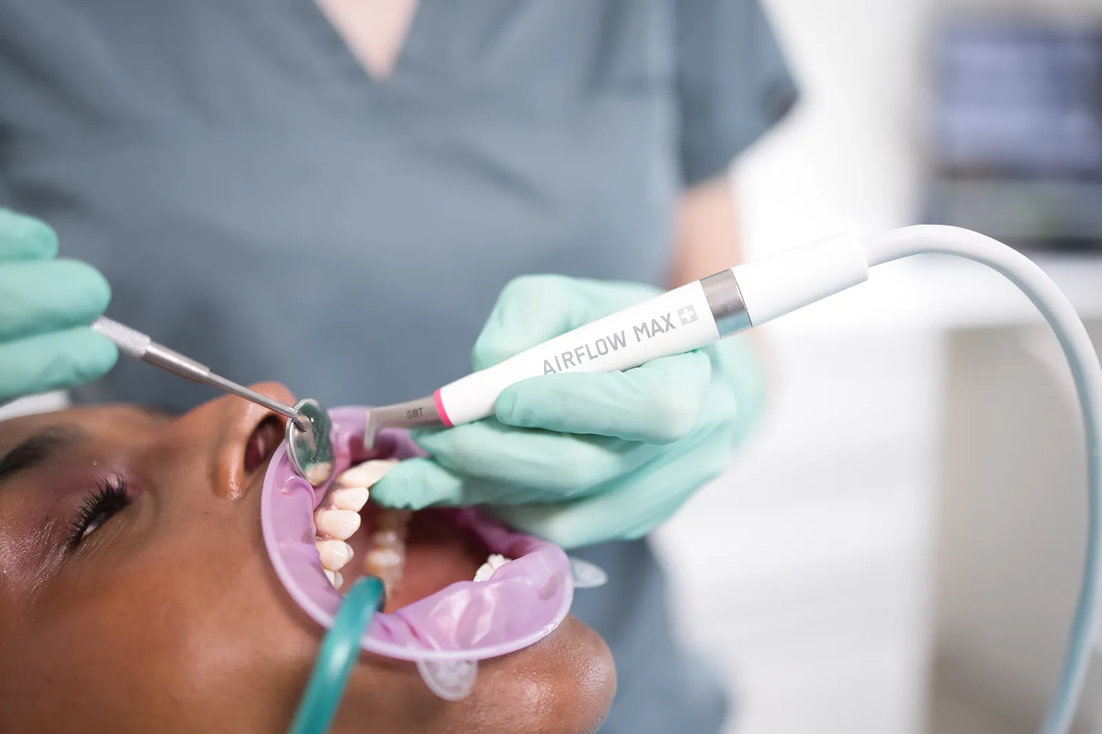 Hygiéniste utilisant un appareil Airflow Max avec embout GBT pendant une séance d'hygiène dentaire